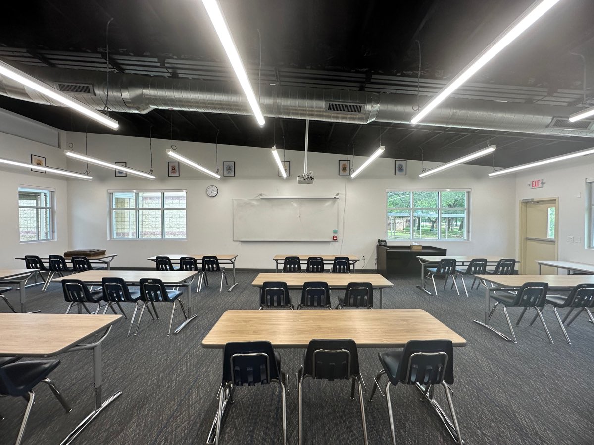 Before: a classroom of folding tables and plastic chairs facing a whiteboard, without a single book in the room.