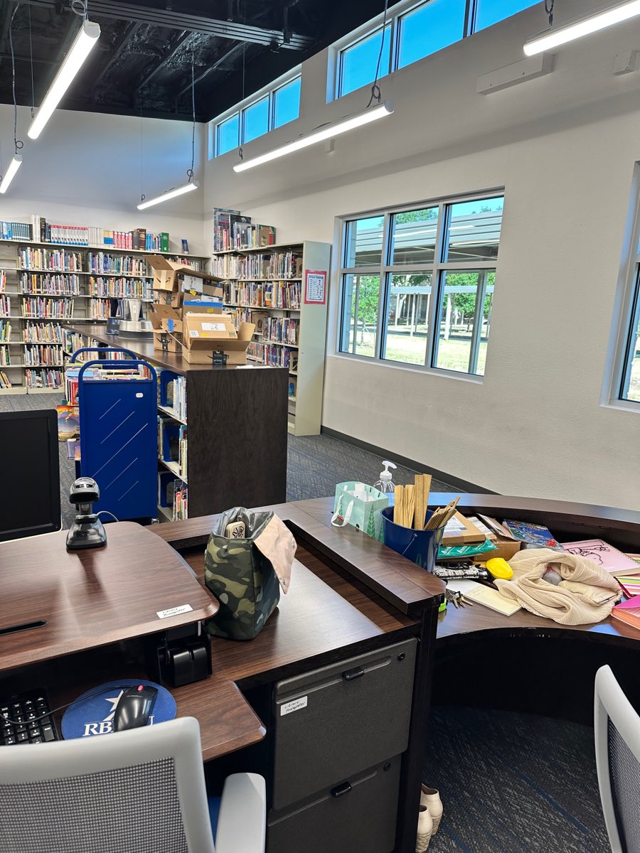 Before: the circulation desk buried under boxes and packing, the shelves beyond unsorted.